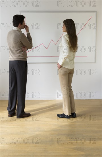 USA, New Jersey, Jersey City, Businessman and woman observing line graph.