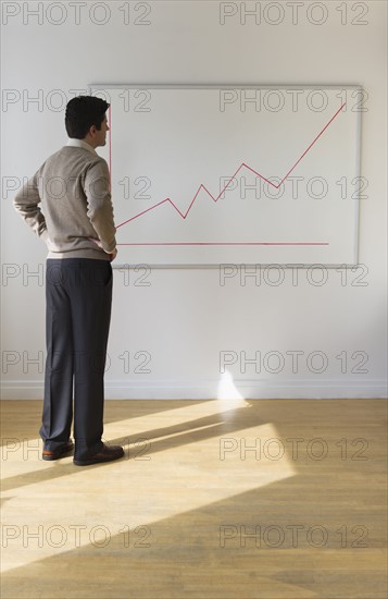 USA, New Jersey, Jersey City, Businessman observing line graph.