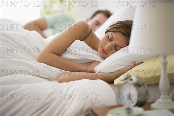 USA, New Jersey, Jersey City, Young couple sleeping in bed.