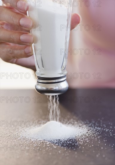 USA, New Jersey, Jersey City, Woman hand holding salt shaker upside down. Photo : Jamie Grill Photography