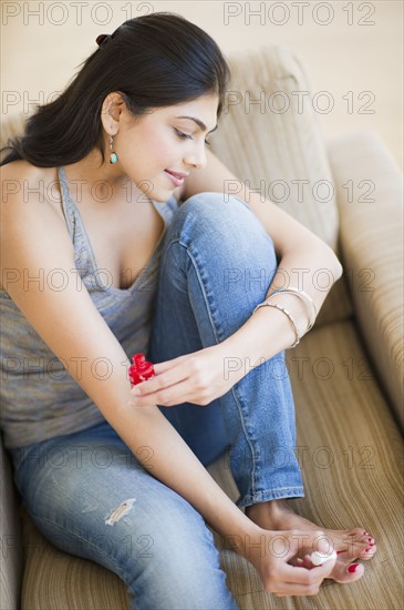 USA, New Jersey, Jersey City, Young attractive painting toenails. Photo : Daniel Grill