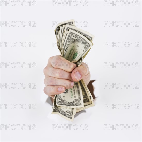 Hand on white background holding banknotes. Photo : Daniel Grill