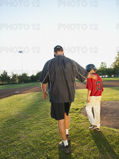 USA, California, Ladera Ranch, man and boy (10-11) walking on baseball field.