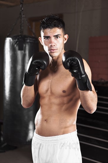 USA, Seattle, Portrait of young man in gym wearing boxing gloves. Photo : Take A Pix Media