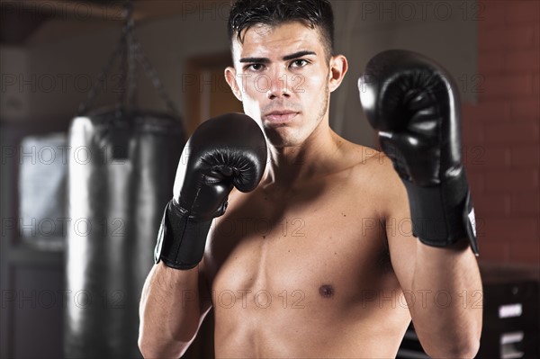 USA, Seattle, Portrait of young man in gym wearing boxing gloves. Photo : Take A Pix Media