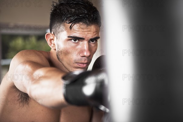 USA, Seattle, Portrait of young man in gym wearing boxing gloves. Photo : Take A Pix Media