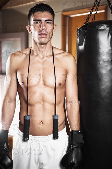 USA, Seattle, Portrait of young man in gym wearing boxing gloves. Photo : Take A Pix Media