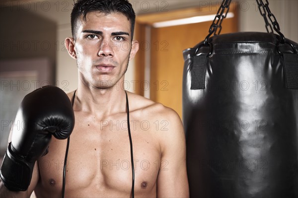 USA, Seattle, Portrait of young man in gym wearing boxing gloves. Photo : Take A Pix Media