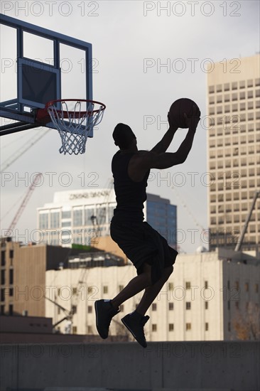USA, Utah, Salt Lake City, Silhouette of young man playing basketball. Photo : Mike Kemp