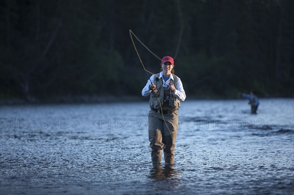 Canada, British Columbia, Fernie, Portrait of woman fly fishing in river. Photo : Dan Bannister