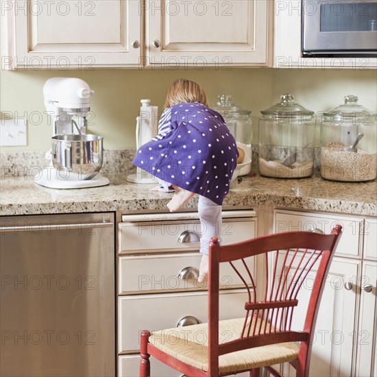 USA, Utah, Girl (2-3) climbing on cupboard in kitchen. Photo : Tim Pannell