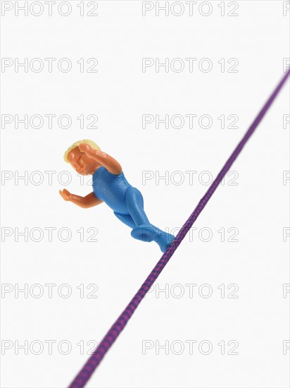 Studio shot of figurine balancing on tightrope. Photo : David Arky