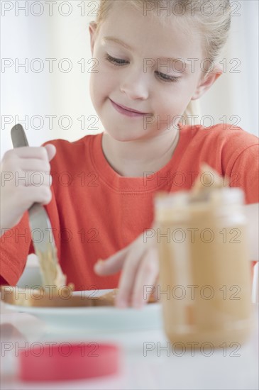 USA, New Jersey, Jersey City, Gil spreading peanut butter over chunk of bread. Photo : Jamie Grill Photography