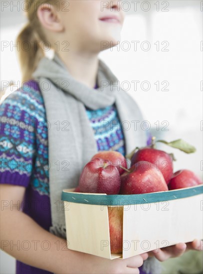 USA, New Jersey, Jersey City, Girl (8-9) holding box of apples. Photo : Jamie Grill Photography