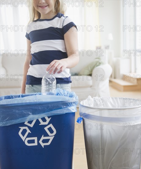 USA, New Jersey, Jersey City, Girl (8-9) putting plastic bottle into recycling bin. Photo : Jamie Grill Photography