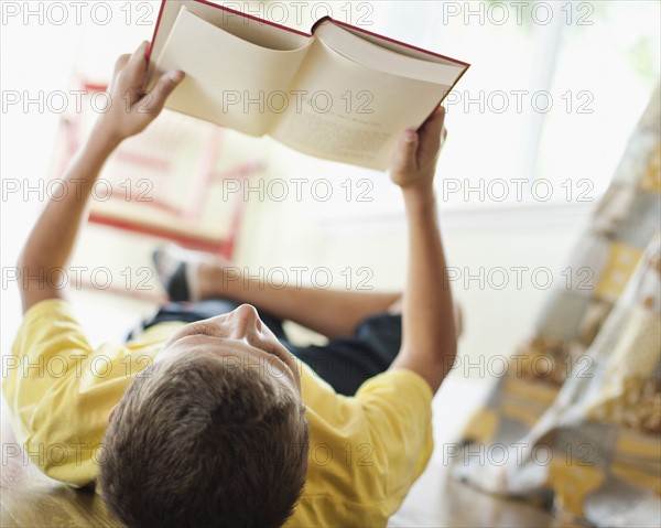 USA, Utah, Boy (10-11) reading book on floor. Photo : Tim Pannell