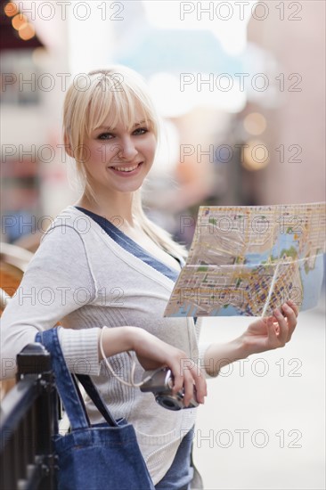 USA, Seattle, Smiling young woman holding map. Photo : Take A Pix Media