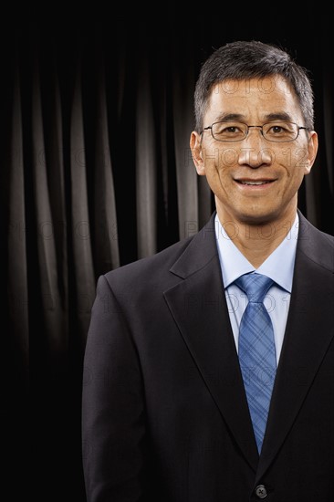 USA, Utah, Provo, Portrait of businessman standing in front of black curtain. Photo : FBP