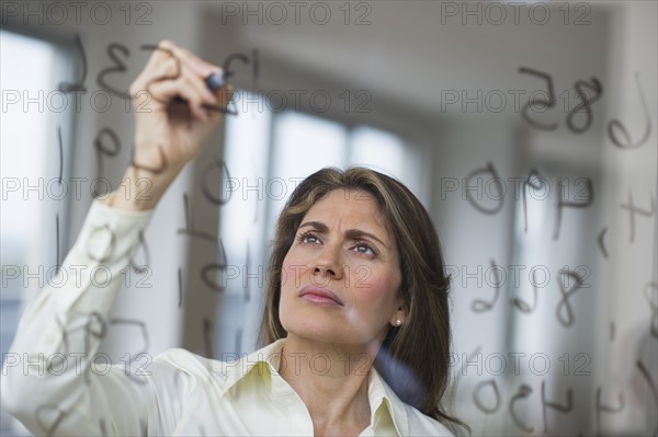 USA, New Jersey, Jersey City, Businesswoman writing calculations on glass.