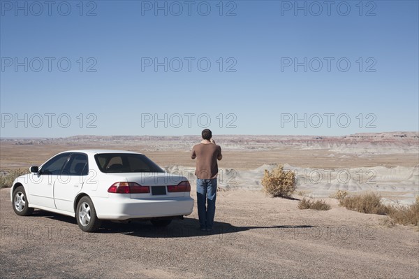 USA, Arizona, Painted Desert. Little Painted Desert, Man standing near car and looking at view. Photo : David Engelhardt