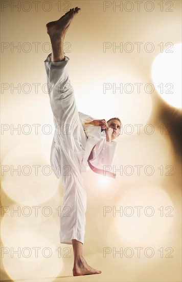 Young man performing karate kick.