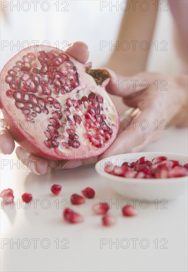 USA, New Jersey, Jersey City, Womans hand with pomegranate cross-section. Photo : Jamie Grill Photography