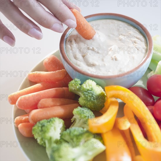 USA, New Jersey, Jersey City, Close-up view of woman hand putting baby carrot into dip. Photo : Jamie Grill Photography