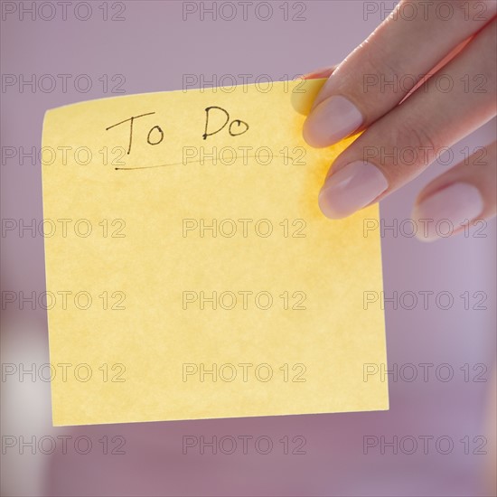 USA, New Jersey, Jersey City, Close-up view of woman hand holding adhesive note for writing down things to do. Photo : Jamie Grill Photography