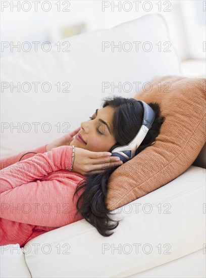 USA, New Jersey, Jersey City, Young attractive woman laying on back listening to music. Photo : Daniel Grill