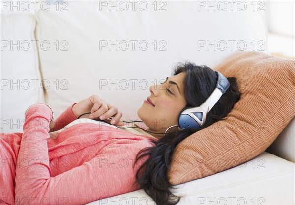 USA, New Jersey, Jersey City, Young attractive woman laying on back listening to music. Photo : Daniel Grill