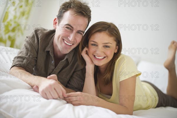 USA, New Jersey, Jersey City, Portrait of young couple lying on bed.