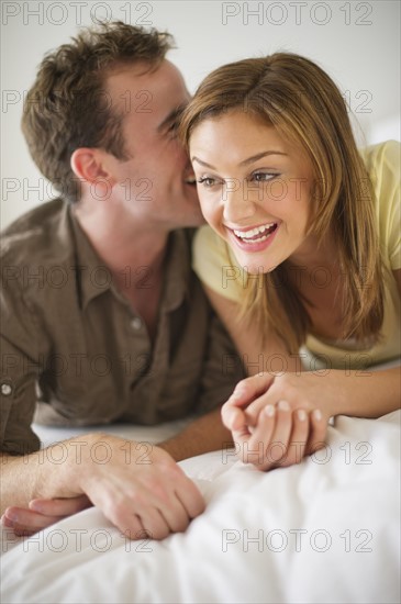 USA, New Jersey, Jersey City, Portrait of young couple lying on bed.