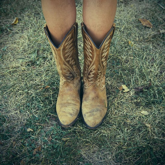 Woman wearing cowboy boots on lawn.