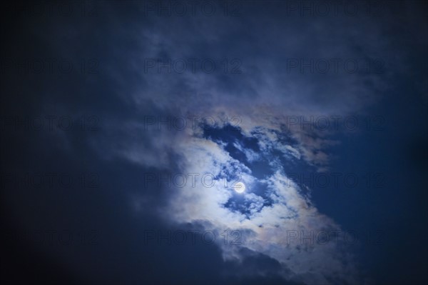 Full moon in cloudy sky at night.