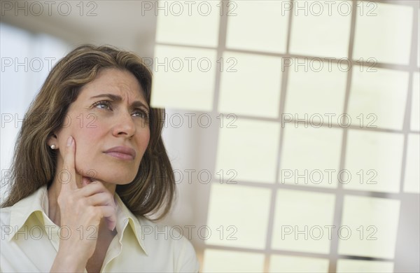USA, New Jersey, Jersey City, Businesswoman observing adhesive notes on window.