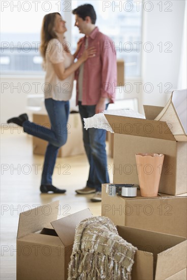 USA, New Jersey, Jersey City, Couple embracing near boxes in new home.