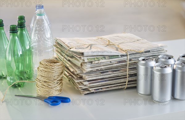 Recycling bottles, cans and newspapers with scissors and string.