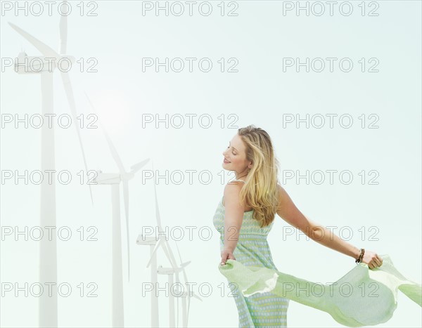 Young woman standing near wind turbines.