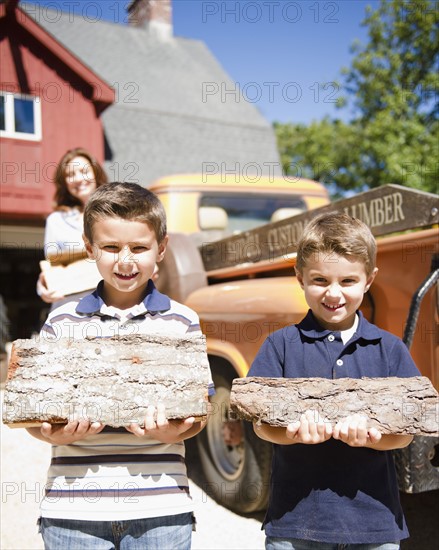 USA, New York, Flanders, Two boys (4-5, 8-9) holding firewood. Photo : Jamie Grill Photography