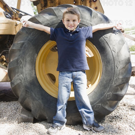USA, New York, Flanders, Boy (4-5) standing in front of tractor wheel. Photo : Jamie Grill Photography