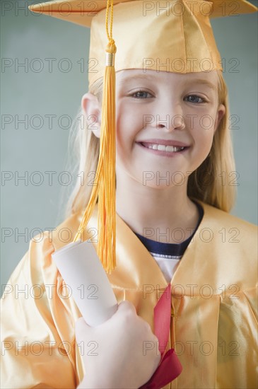 USA, New Jersey, Jersey City, Girl (8-9) wearing yellow mortar board and graduation gown. Photo : Jamie Grill Photography