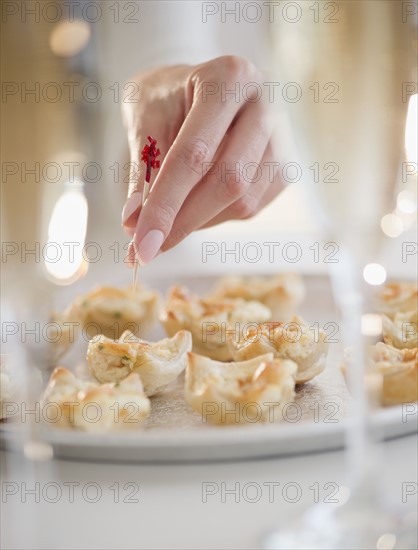 USA, New Jersey, Jersey City, Woman's hand sticking toothpick into fresh snack. Photo : Jamie Grill Photography