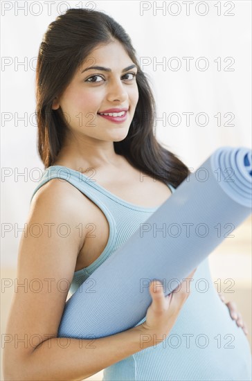 USA, New Jersey, Jersey City, Pregnant young attractive woman with exercising mat. Photo : Daniel Grill
