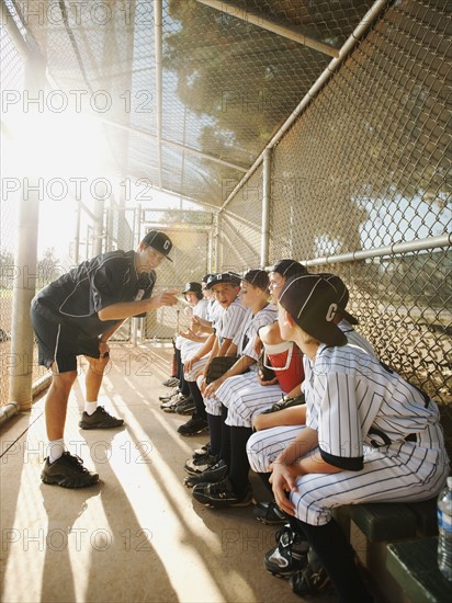 USA, California, Ladera Ranch, Boys (10-11) from little league sitting on dugout while coach talking.