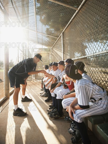 USA, California, Ladera Ranch, coach training little league baseball team (10-11) on dugout.