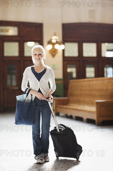 USA, Seattle, Young woman at train station standing with luggage and looking at camera. Photo : Take A Pix Media