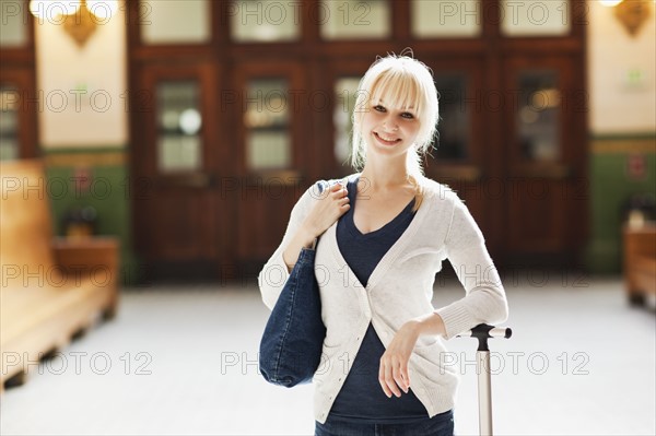 USA, Seattle, Young woman at train station standing with luggage and looking at camera. Photo : Take A Pix Media