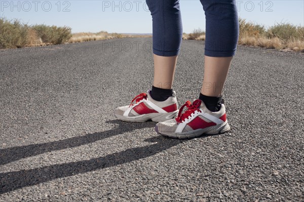 USA, Arizona, Winslow, Mid adult woman wearing spots shoes standing, low section. Photo : David Engelhardt