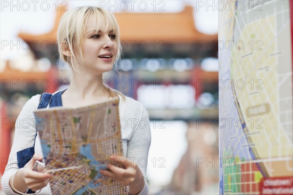 USA, Seattle, Smiling young woman holding map. Photo : Take A Pix Media