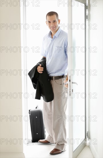 South Africa, Young businessman entering home. Photo : momentimages
